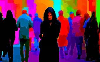 A woman in black stands alone with her arms crossed, looking down, while colorful, blurred figures of people pass by in the vibrant, abstract background.